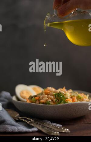 Gießen von Olivenöl auf Bohnen Salat. Gesunde Ernährung Konzept Stockfoto