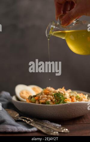 Gießen von Olivenöl auf Bohnen Salat. Gesunde Ernährung Konzept Stockfoto