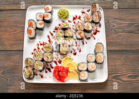 Blick von oben auf das Maki Set, verschiedene Sushi-Sorten. Sake Maki, Kappa Maki, Avocado Maki, Thunfisch Maki verziert mit Unagi-Sauce und Sesam, Zitrone, wa Stockfoto