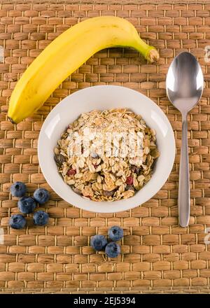 Gesundes Frühstück bestehend aus Cerealien, Banane und Heidelbeeren mit Löffel beiseite Stockfoto