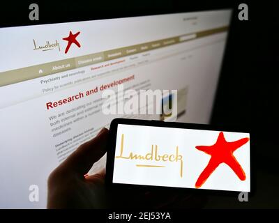 Person, die Mobiltelefon mit Geschäftslogo des dänischen Pharmaunternehmens H. Lundbeck AUF dem Bildschirm vor der Website hält. Konzentrieren Sie sich auf die Telefonanzeige. Stockfoto