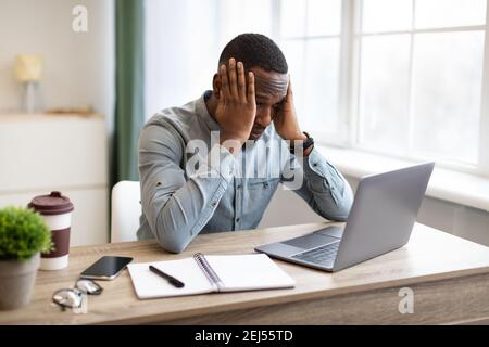 Afrikanischer Geschäftsmann Am Laptop Berühren Kopf Mit Problem Am Arbeitsplatz Stockfoto