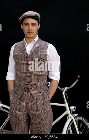 Hübscher kaukasischer Mann, der neben dem Fahrrad steht und stilvolle Tweed-Kleidung trägt Stockfoto