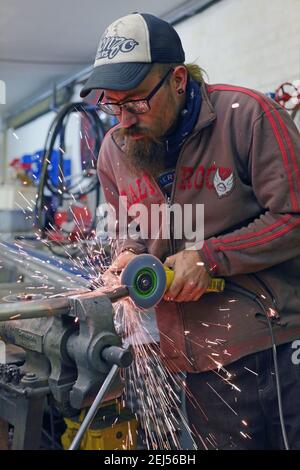 Mann, der mit Elektrowerkzeugen arbeitet und Metall mit Winkel schneidet Ginder in der Werkstatt Stockfoto