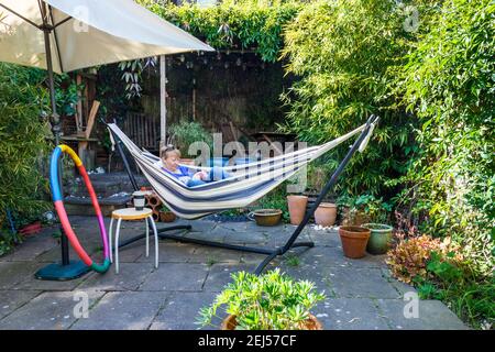 Eine Frau, die es einfach in einer Hängematte in einem Nordlondonterasse Garten, Großbritannien nimmt Stockfoto