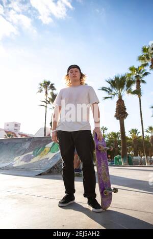 Junger Skater mit seinem Skateboard in der Hand im Skatepark Stockfoto