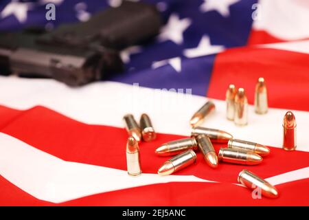 Viele gelbe 9mm Kugeln und Pistole auf US-Flagge. Konzept des Waffenhandels auf US-Territorium oder US-Schießstand Stockfoto