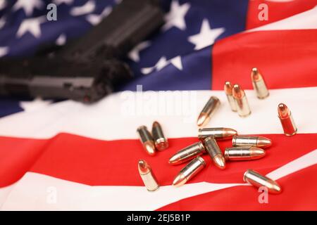 Viele gelbe 9mm Kugeln und Pistole auf US-Flagge. Konzept des Waffenhandels auf US-Territorium oder US-Schießstand Stockfoto