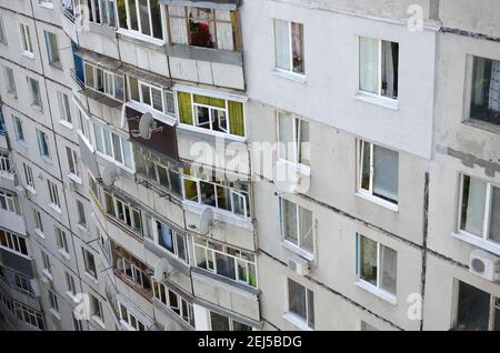 Fassade eines grauen mehrstöckigen sowjetischen Paneelgebäudes. Russische alte urbane Wohnhäuser mit Fenstern und Balkon. Typische russische Nachbarschaft Stockfoto