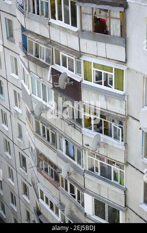 Fassade eines grauen mehrstöckigen sowjetischen Paneelgebäudes. Russische alte urbane Wohnhäuser mit Fenstern und Balkon. Typische russische Nachbarschaft Stockfoto