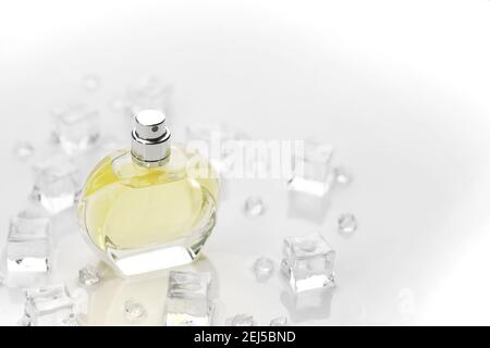Weibliche Parfüm gelbe Flasche, objektive Foto von Parfüm-Flasche in Eiswürfeln und Wasser auf weißem Tisch. Blick von oben. Modellbild Produktfoto, Kontra Stockfoto