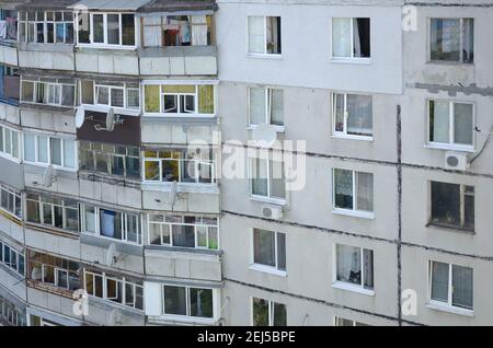 Fassade eines grauen mehrstöckigen sowjetischen Paneelgebäudes. Russische alte urbane Wohnhäuser mit Fenstern und Balkon. Typische russische Nachbarschaft Stockfoto