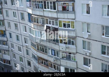 Fassade eines grauen mehrstöckigen sowjetischen Paneelgebäudes. Russische alte urbane Wohnhäuser mit Fenstern und Balkon. Typische russische Nachbarschaft Stockfoto