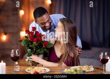 Loving African American Guy Überraschend Seine Schöne Freundin Mit Rosen Bouquet Stockfoto