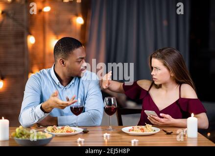 Genervt Schwarz Kerl Schuld Seine Freundin Für Die Verwendung Smartphone Während Romantisches Abendessen Stockfoto