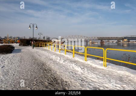 Tczew, Polen - 21. Februar 2021: Uferpromenade Weichsel in Tczew. Die historische Brücke im Hintergrund. Polen. Stockfoto