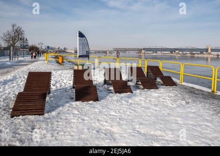 Tczew, Polen - 21. Februar 2021: Entspannungszone an der Uferpromenade in Tczew. Die historische Brücke im Hintergrund Stockfoto