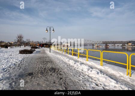 Tczew, Polen - 21. Februar 2021: Uferpromenade Weichsel in Tczew. Die historische Brücke im Hintergrund. Polen. Stockfoto