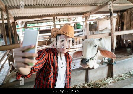 Ein Bauer trägt einen Selfie Cowboy Hut mit einem Smartphone Stockfoto