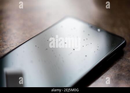Smartphone-Bildschirm mit gehärtetem Glas zum Schutz vor Kratzern. Wassertropfen auf dem Bildschirm. Reinigen des Touchscreens. Stockfoto
