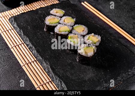 Sushi-Brötchen mit Avocado und Lachs. Klassisches japanisches Sushi. Draufsicht. Freier Speicherplatz für Ihren Text. Stockfoto