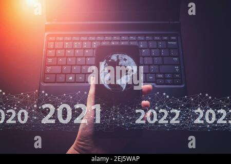 Zeigt virtuelle Hologramm Globus, Welt 2021 auf Smartphone und Tastatur Laptop Hintergrund. Konzept für das neue Jahr 2021. Schutz personenbezogener Daten Stockfoto