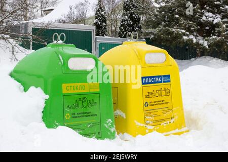 Grüne und gelbe Behälter zur getrennten Abfallsammlung für Glas und Kunststoff. Boxen für die getrennte Sammlung von Müll im Winter. Stockfoto