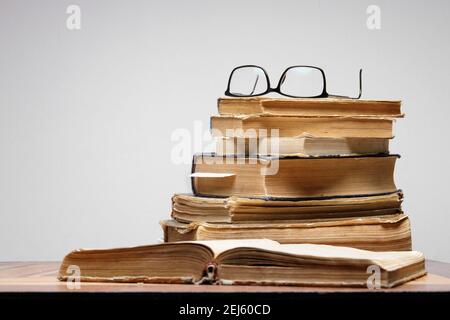 Stapel von alten Büchern mit Lesezeichen auf Holztisch. Gläser sind oben Stockfoto