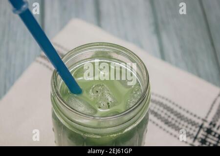 Horizontales Bild Iced Matcha Tee auf blauem Holz Hintergrund mit einem Kaminsims. Japanischer Grüner Tee Konzept. Zubereitung Von Matcha-Tee 2021. Stockfoto