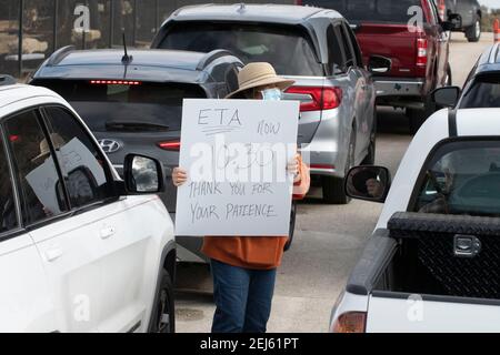 Oak Hill, TX USA 21. Feb. 2021: Freiwillige Cherry ward hilft bei der Organisation einer langen Reihe von Fahrzeugen an einer Wasserabfüllanlage im westlichen Travis County, TX. Die Bewohner der Gegend haben seit mehreren Tagen kein fließendes Wasser mehr, weil letzte Woche der verheerende Schneesturm in Texas war. Fahrer durften nur einen Koffer pro Auto, nachdem einige drei Stunden in der Schlange standen. Kredit: Bob Daemmrich/Alamy Live Nachrichten Stockfoto