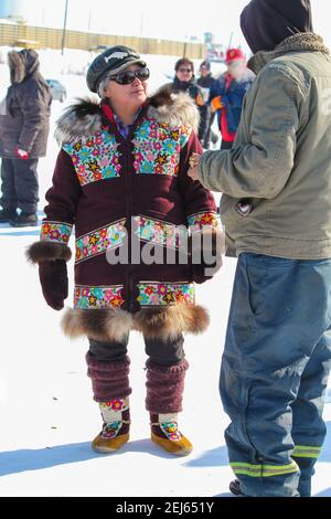 Indigene Frau im traditionellen Parka spricht mit Mann auf Inuviks Muskrat Jamboree Festival im Winter, Northwest Territories, Kanadas westliche Arktis. Stockfoto