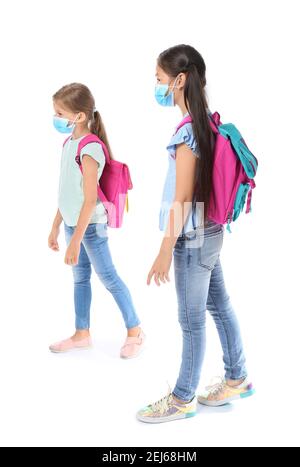 Kleine Schüler in medizinischen Masken auf weißem Hintergrund. Coronavirus-Epidemie Stockfoto