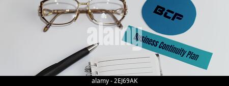 Papier mit den Worten BCP Business Continuity Plan. In der Nähe befinden sich eine Brille, ein Stift und ein Notizblock. Stockfoto