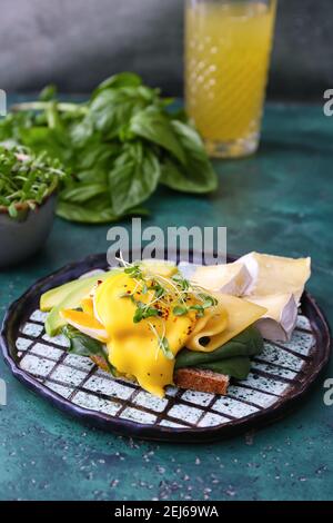 Leckeres Sandwich mit florentiner Ei, Käse und Avocado auf farbigem Hintergrund Stockfoto