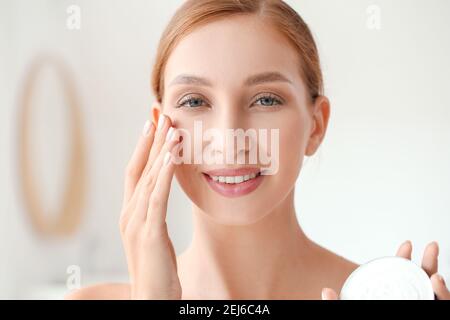Schöne junge Frau Anwendung Gesichtscreme im Badezimmer, Nahaufnahme Stockfoto
