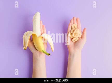 Frau hält frische Banane und knusprige Chips auf Farbhintergrund Stockfoto