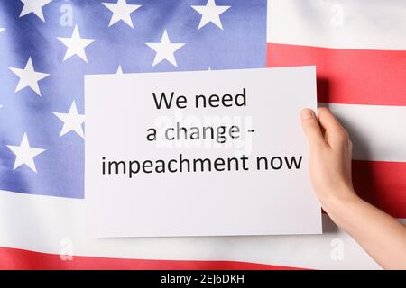 Hand halten Papier mit Text BRAUCHEN WIR EINE ÄNDERUNG - AMTSENTHEBUNG JETZT gegen USA Flagge Stockfoto