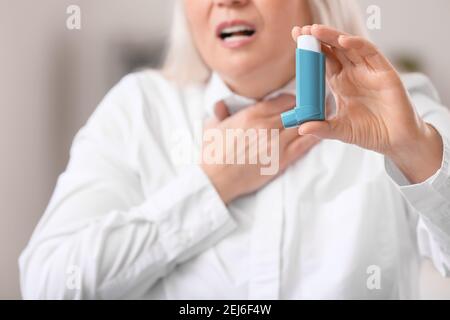 Reife Frau mit Inhalator mit Asthmaanfall im Büro Stockfoto