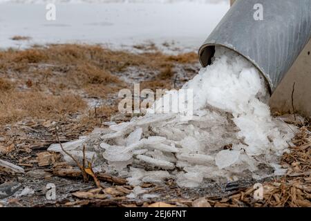 Eis fließt aus dem Boden eines Ablaufrohres. Dies ist ein Rohr, das zum Ablassen von Wasser aus einer großen Brücke verwendet wird. Es ist in einem Winkel von 45 Grad zum Boden. Stockfoto