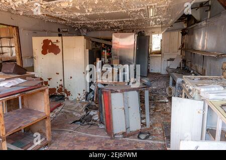 Blick in die Küche eines verlassenen Motels. Kaputte Geräte und Zähler sichtbar, viel Schmutz, beschädigte Decke und Boden. Stockfoto