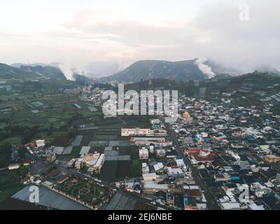 Luftaufnahme des Dorfes Dieng bei Wonosobo mit Berg ringsum IT Stockfoto