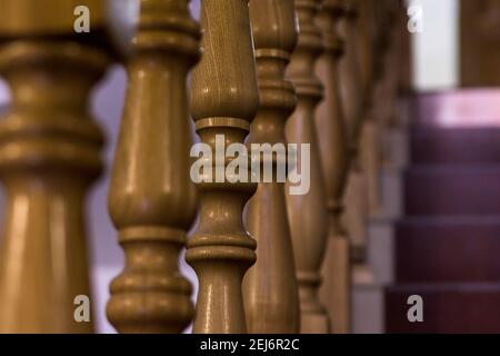 Holzbaluster auf dunkelroter Treppe im Innenbereich, selektiver Fokus Stockfoto