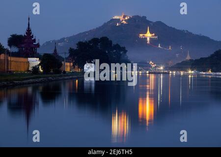 Palace Graben und Mandalay Hill bei Nacht, Mandalay, Myanmar. Die Su Taung Pyae Pagode kann auf der Spitze mit dem Shweyattaw Buddha Pavillon Halb w gesehen werden Stockfoto