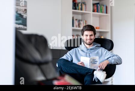 Düsseldorf, Deutschland. Februar 2021, 19th. Student und Bestseller-Autor Tim Nießner sitzt mit seinem neuen Buch "der Zeugnisretter" in einem Sessel. Nießner aus Haan bei Düsseldorf hat systematisch die Strategien der besten Studierenden Deutschlands erforscht. In seinem Buch hat er dabei eine Menge Tipps für schlechte Schüler. (To dpa 'Operation Zeugnisrettung: Wie schlechte Schüler die Kurse kriegen') Quelle: Fabian Strauch/dpa/Alamy Live News Stockfoto