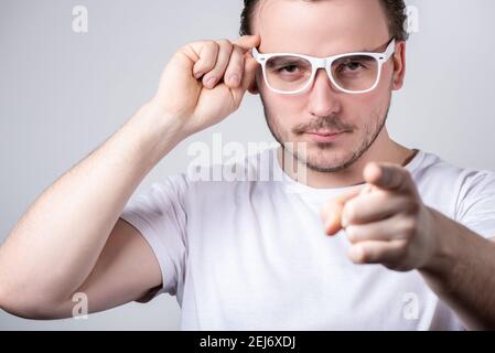 Schöner Brünette Mann mit Brille zeigt einen Finger nach vorne auf Ein weißer Hintergrund Stockfoto
