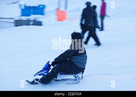 Umea, Norrland Schweden - 8. Februar 2021: Ein kleiner Junge rutscht die Skipiste hinunter Stockfoto