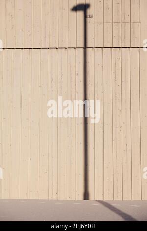 Der Schatten eines Laternenpfostens an einer Hausfassade Stockfoto