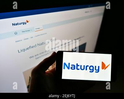 Person mit Mobiltelefon mit Logo des spanischen Energieunternehmens Naturgy Energy Group S.A. auf dem Bildschirm vor der Webseite. Fokus auf Handy-Display. Stockfoto