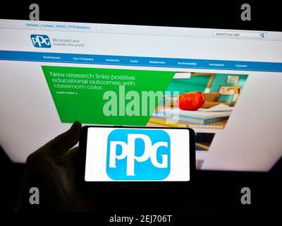 Person, die Smartphone mit Logo des US-Chemieunternehmens PPG Industries Inc. Auf dem Bildschirm vor der Website hält. Konzentrieren Sie sich auf die Telefonanzeige. Stockfoto