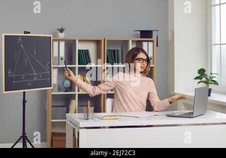 Schule Mathe Lehrer sitzen am Schreibtisch mit Laptop und geben Online-Geometrie-Lektion Stockfoto